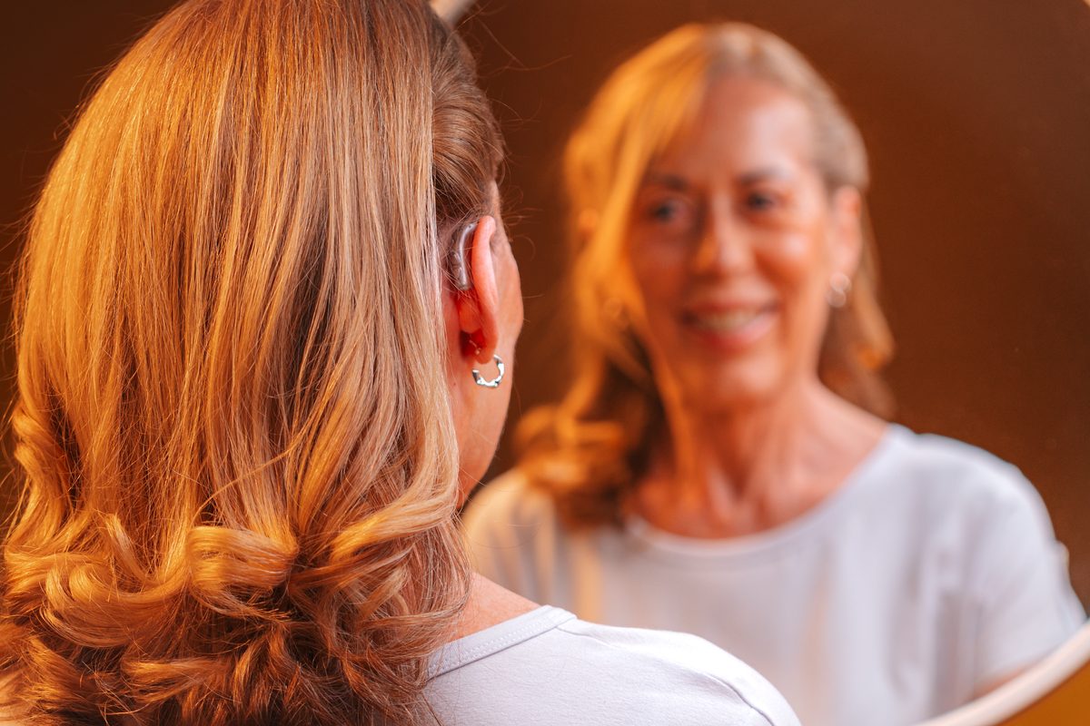 Paciente sorrindo ao lado de familiar, usando aparelho auditivo Philips